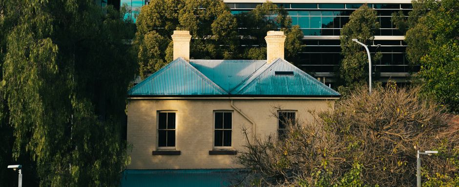 Photograph of several multi-storey residential buildings with a mix of architectural styles, including stucco and brick facades, and various window designs. Some roofs are sloped with chimneys, and a